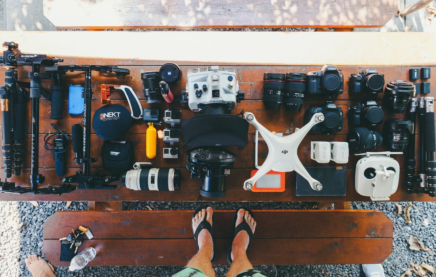 Various camera equipment and drones laid out on a wooden table.